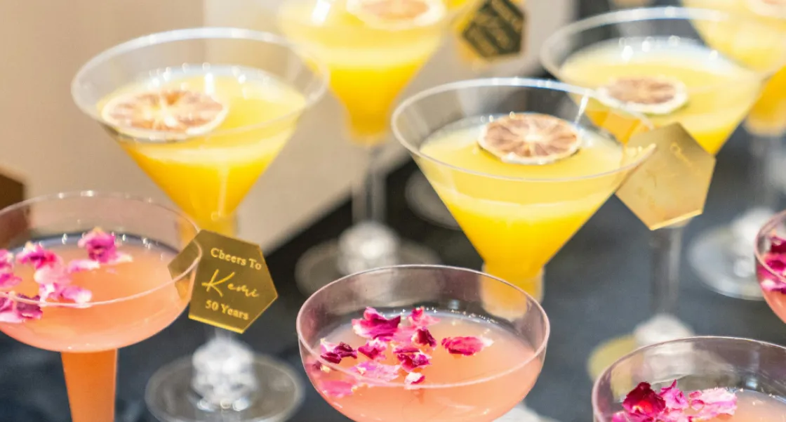 Handcrafted cocktail drinks garnished with dried citrus and rose petals served at a Peter Rowland event.