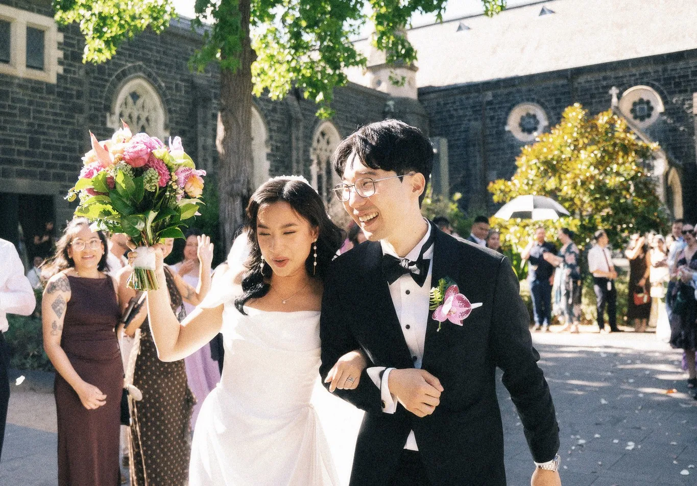 Bride and groom walking outside a heritage bluestone venue featuring bespoke wedding catering services by Peter Rowland.