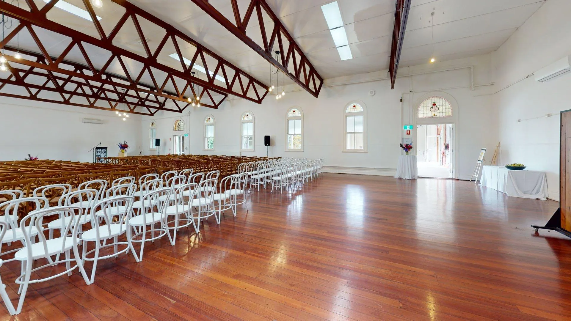Bright indoor function space set up with rows of white chairs for a private event catered by Peter Rowland.