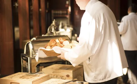 Professional Peter Rowland chef serving warm gourmet dishes at an elegant buffet catering station.
