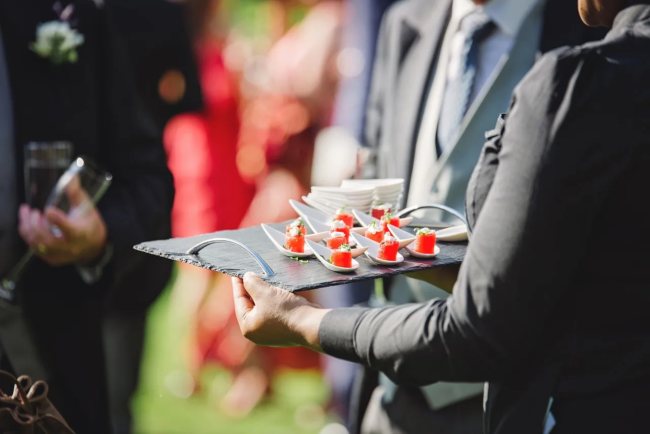Peter Rowland waitstaff serving delicate gourmet canapés on a slate tray during a luxury wedding cocktail reception.