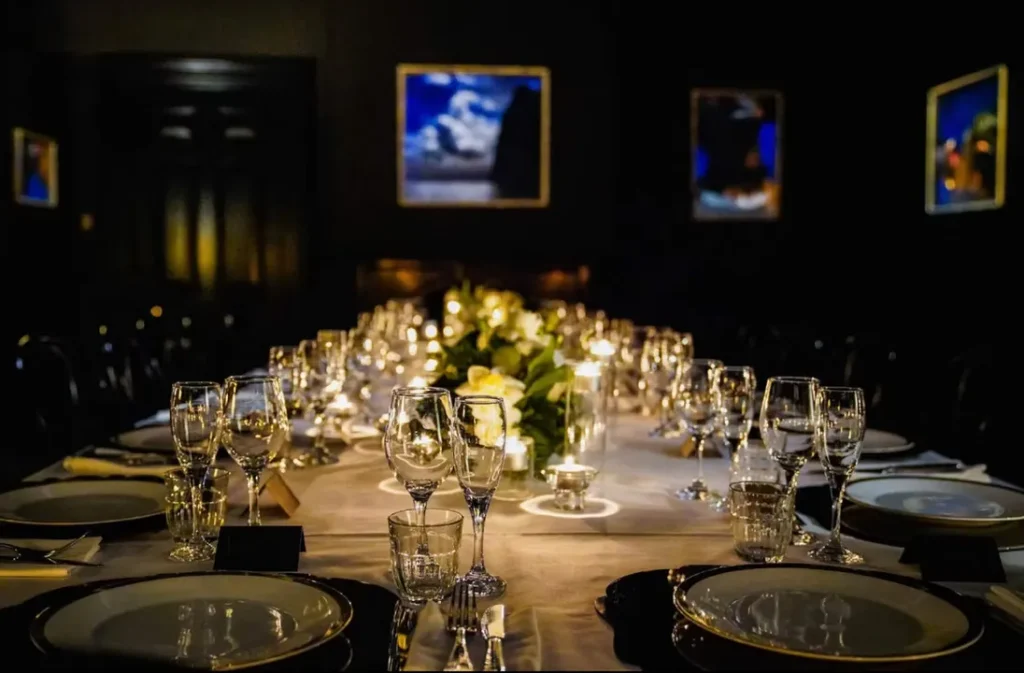Opulent candlelit banquet table setup for an intimate dinner inside the Hellenic Museum art gallery.