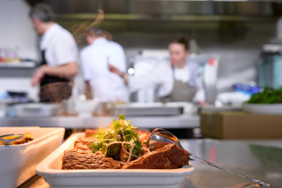 Peter Rowland chef preparing fresh ingredients in a stainless steel container for event catering.