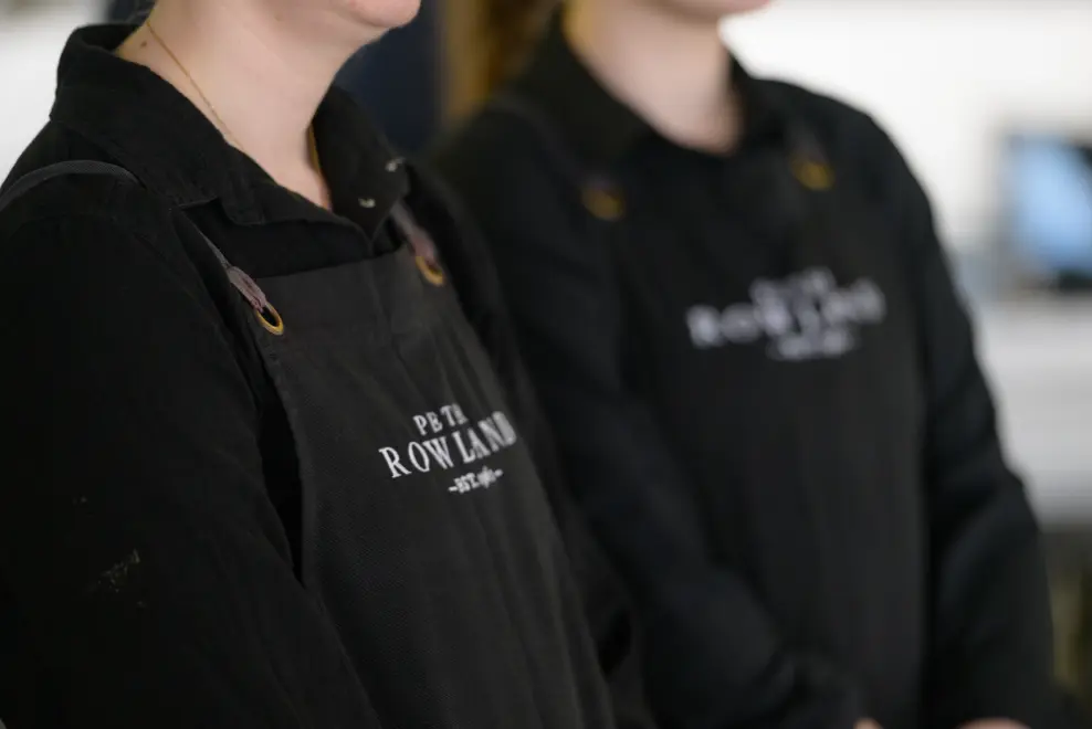 Peter Rowland hospitality staff wearing branded black aprons ready for corporate event service.