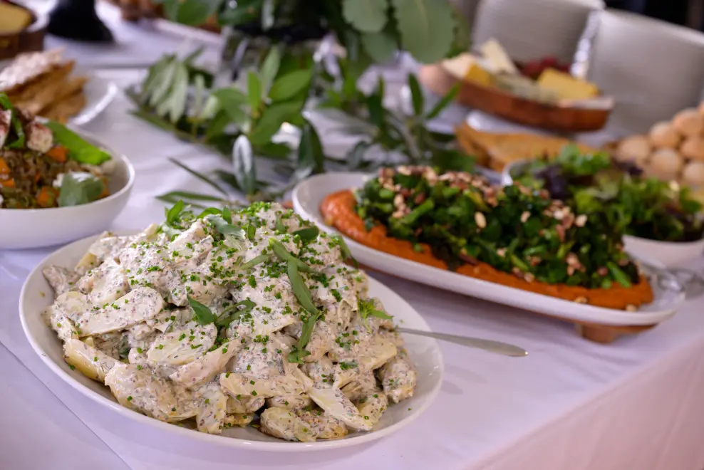 Gourmet artisanal salads and fresh green dishes displayed on a corporate catering buffet table.