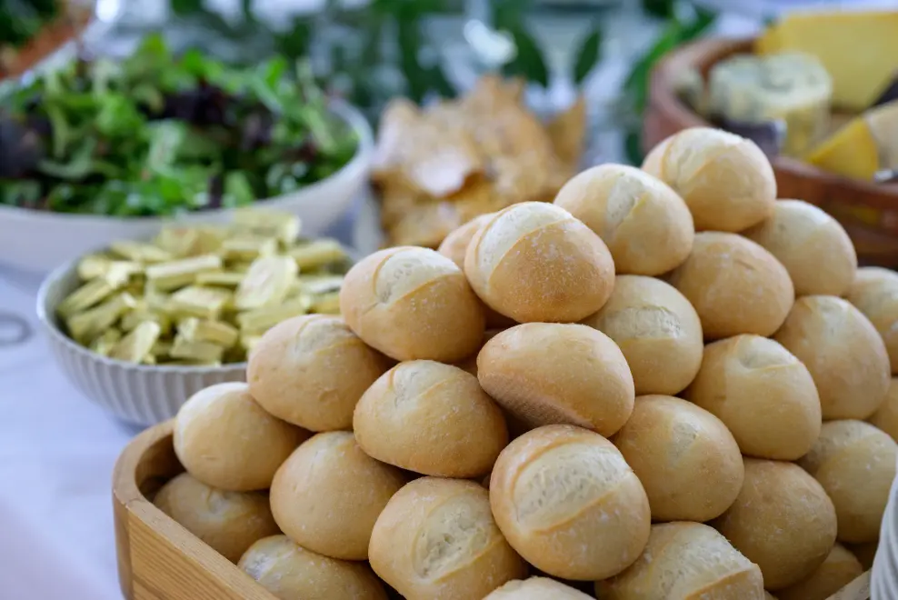 Freshly baked artisanal dinner rolls stacked on a corporate event catering food display.